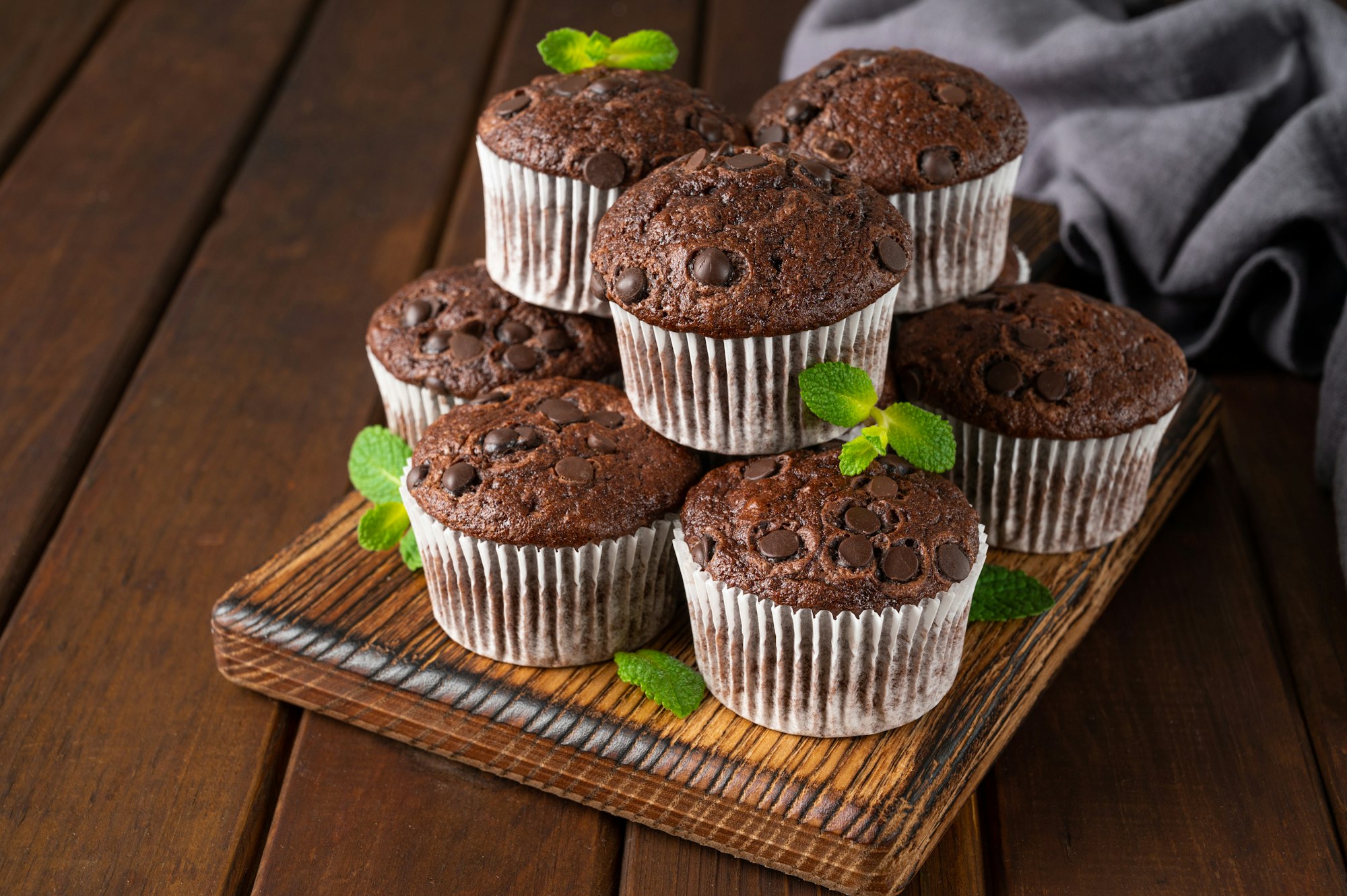 Chocolate muffins or cupcakes with chocolate drops and mint. Copy space.