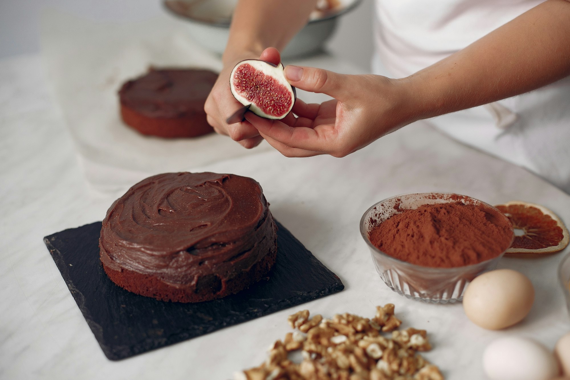 Confectioner decorates a chocolate cake with figs.