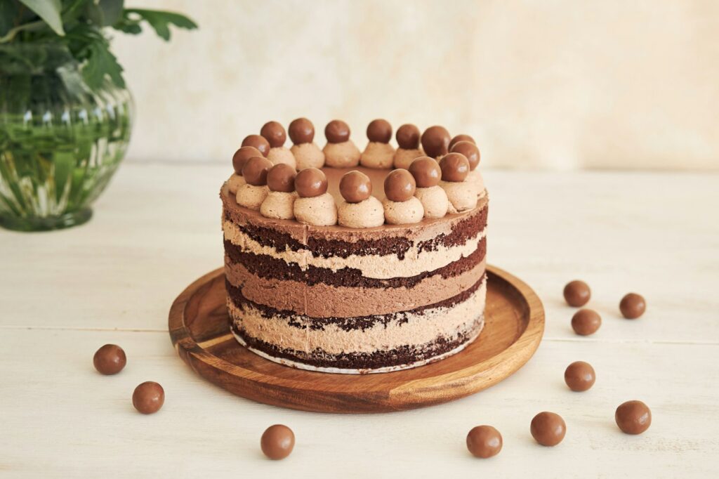 Delicious chocolate naked cake with choco balls and cream on a white table